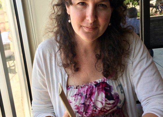 Kate Roff sitting at a coffee shop, pen and paper in hand.