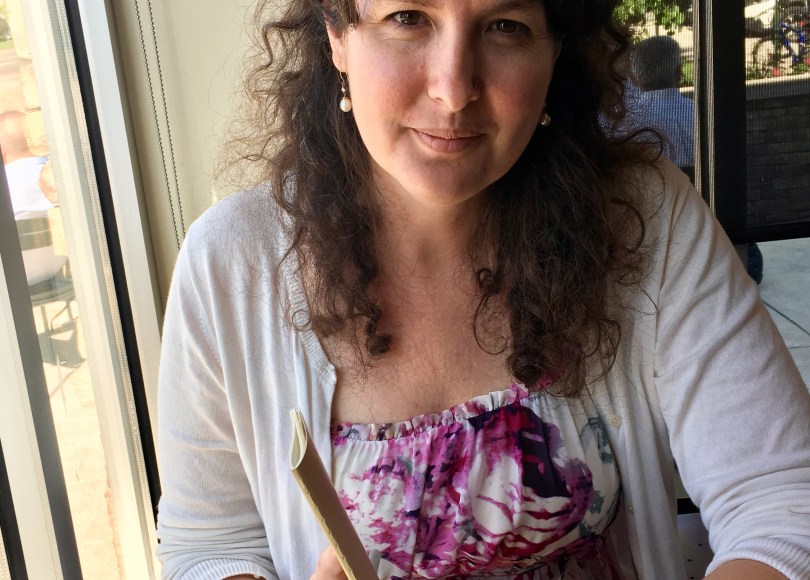 Kate Roff sitting at a coffee shop, pen and paper in hand.