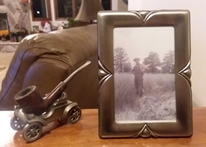 Framed black-and-white image of farmer, next to pipe sculpture.