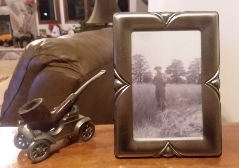 Framed black-and-white image of farmer, next to pipe sculpture.