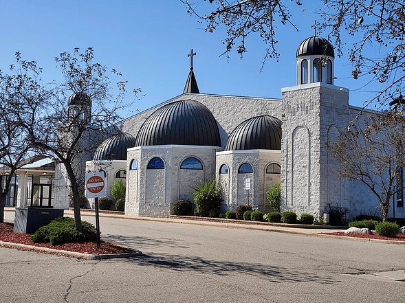 Church, white walls, black cross on roof against blue sky