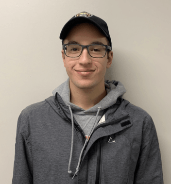 Young man with Oakland University baseball cap smiles.
