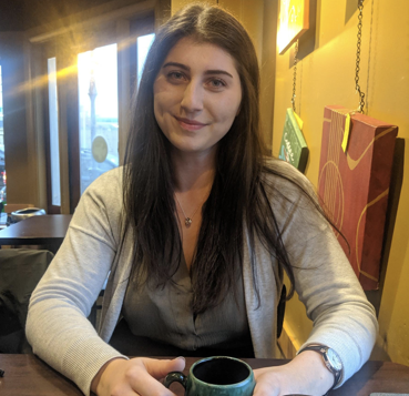 Woman smiles at camera while holding cup of tea