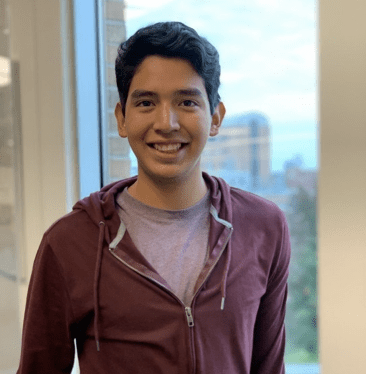 Young man smiles, poses by window.