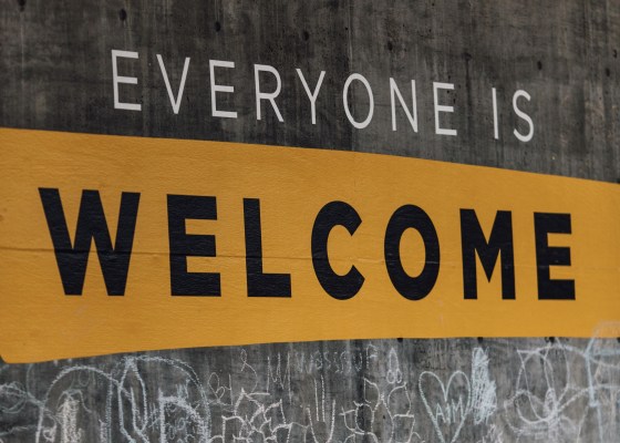Sign in all caps "Everyone is welcome" on blackboard, scribbles and drawings in chalk below