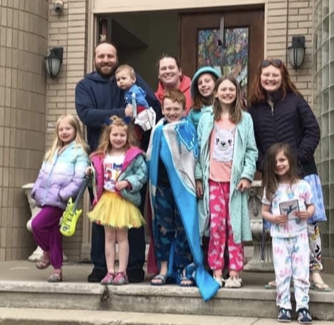 Family of ten smiling standing on steps of building