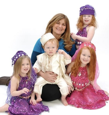 Woman smiles posing with four small children, outfits in Middle Eastern style