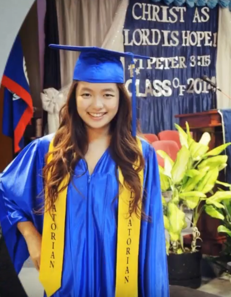 Young woman of Asian heritage smiles in graduation outfit