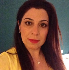 Close-up of middle aged white woman, long dark brown hair framing her face, neutral expression