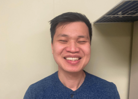Close-up of smiling young man of Asian descent, short black hair, blue shirt