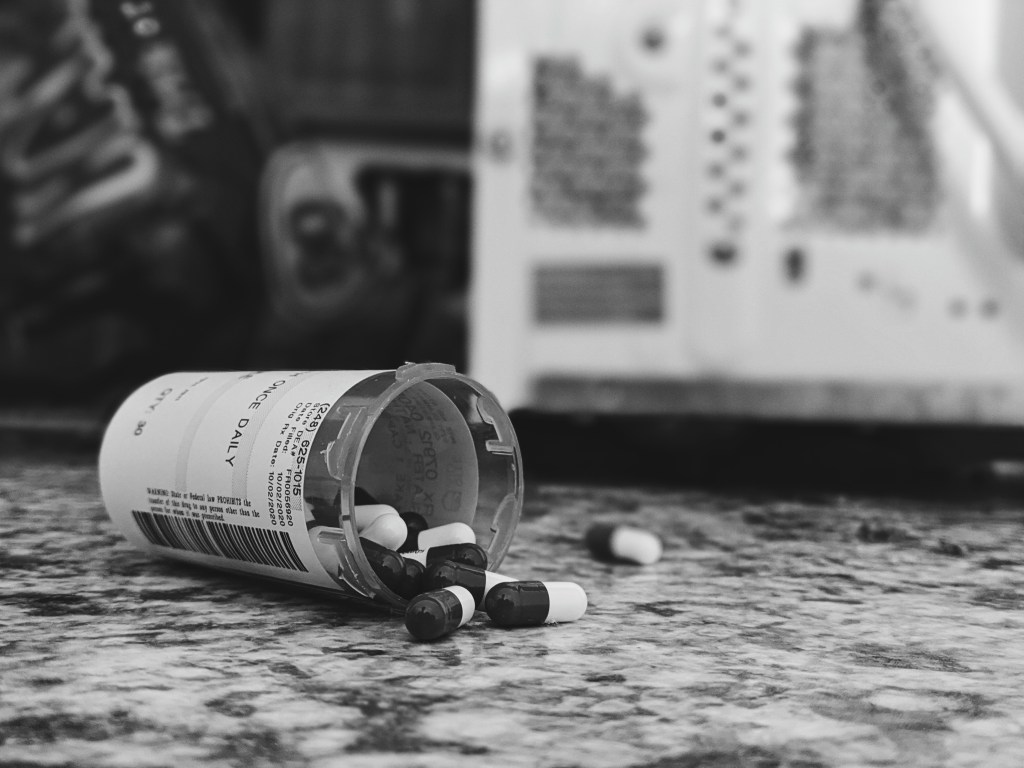Close-up of bottle of medicine spilling pills on countertop